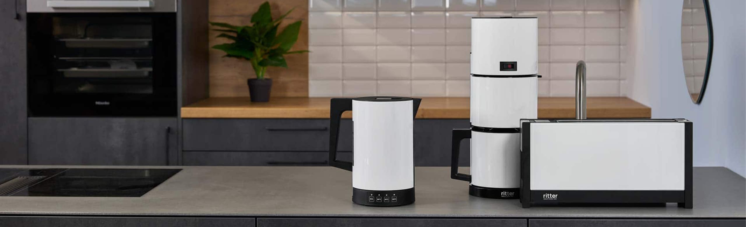 A picture of a white toaster, kettle and coffee machine standing next to each other on a kitchen platform.