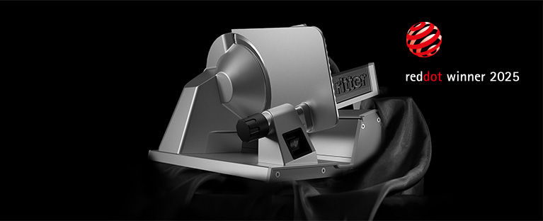 Ein Bild von einem Feinschneider, der aus einem schwarzen Tuch hervorkommt, und einer reddot winner 2025 Auszeichnung.