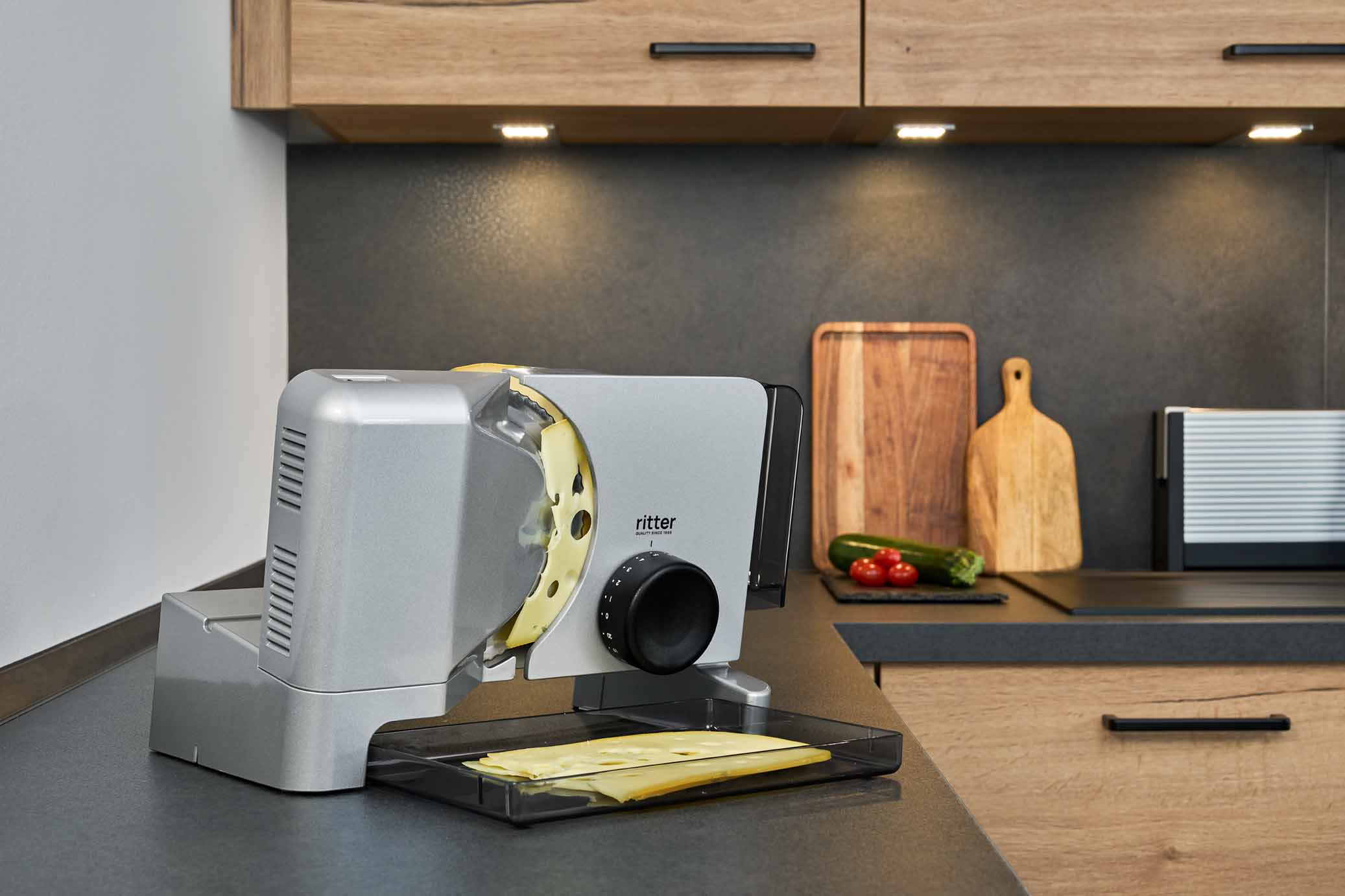 Elektrischer Allesschneider mit geschnittenem Käse, in moderner Küche
