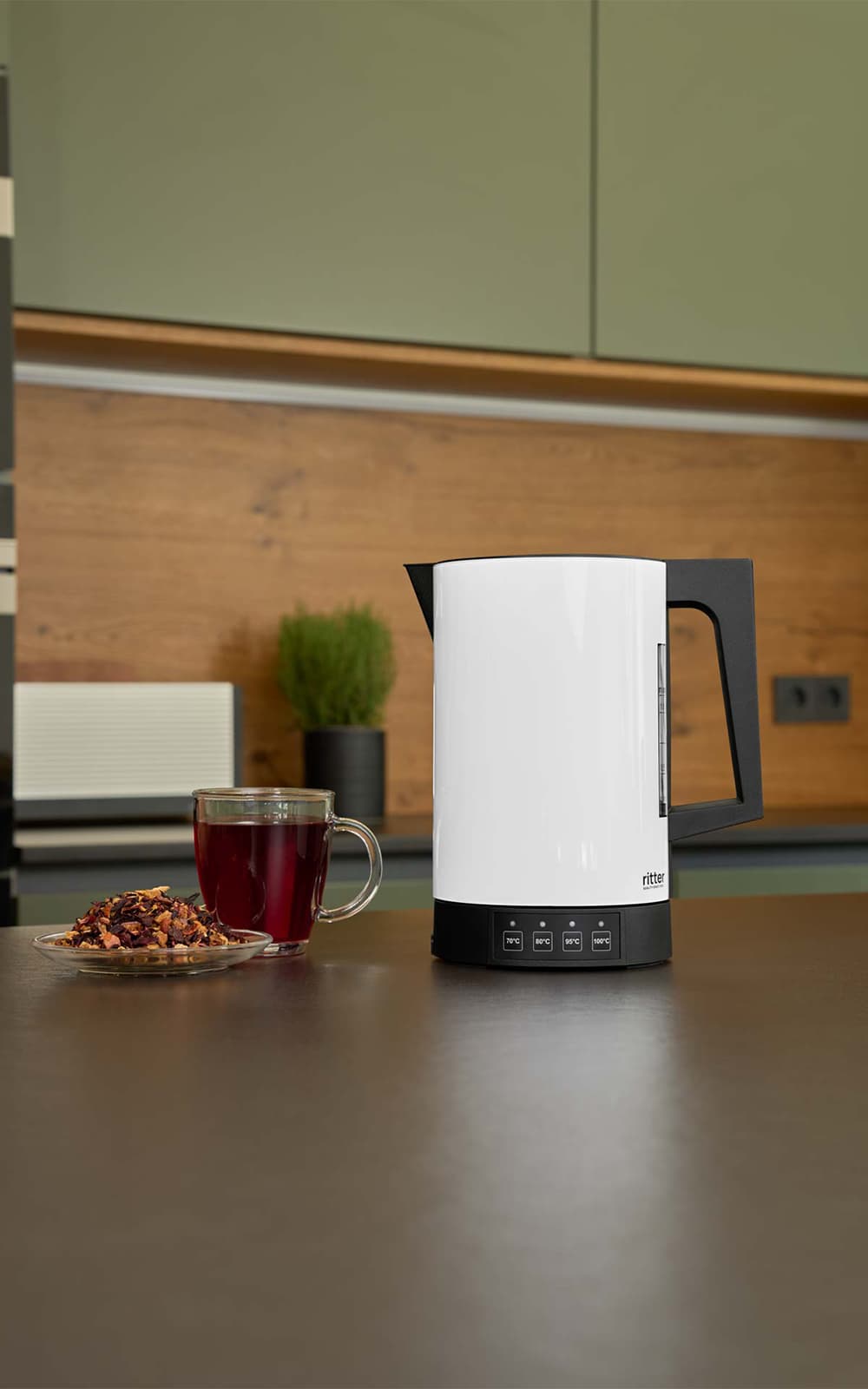 A picture of the white kettle standing on a kitchen platform next to a cup of tea. A picture of the white kettle standing on a kitchen platform next to a cup of tea.