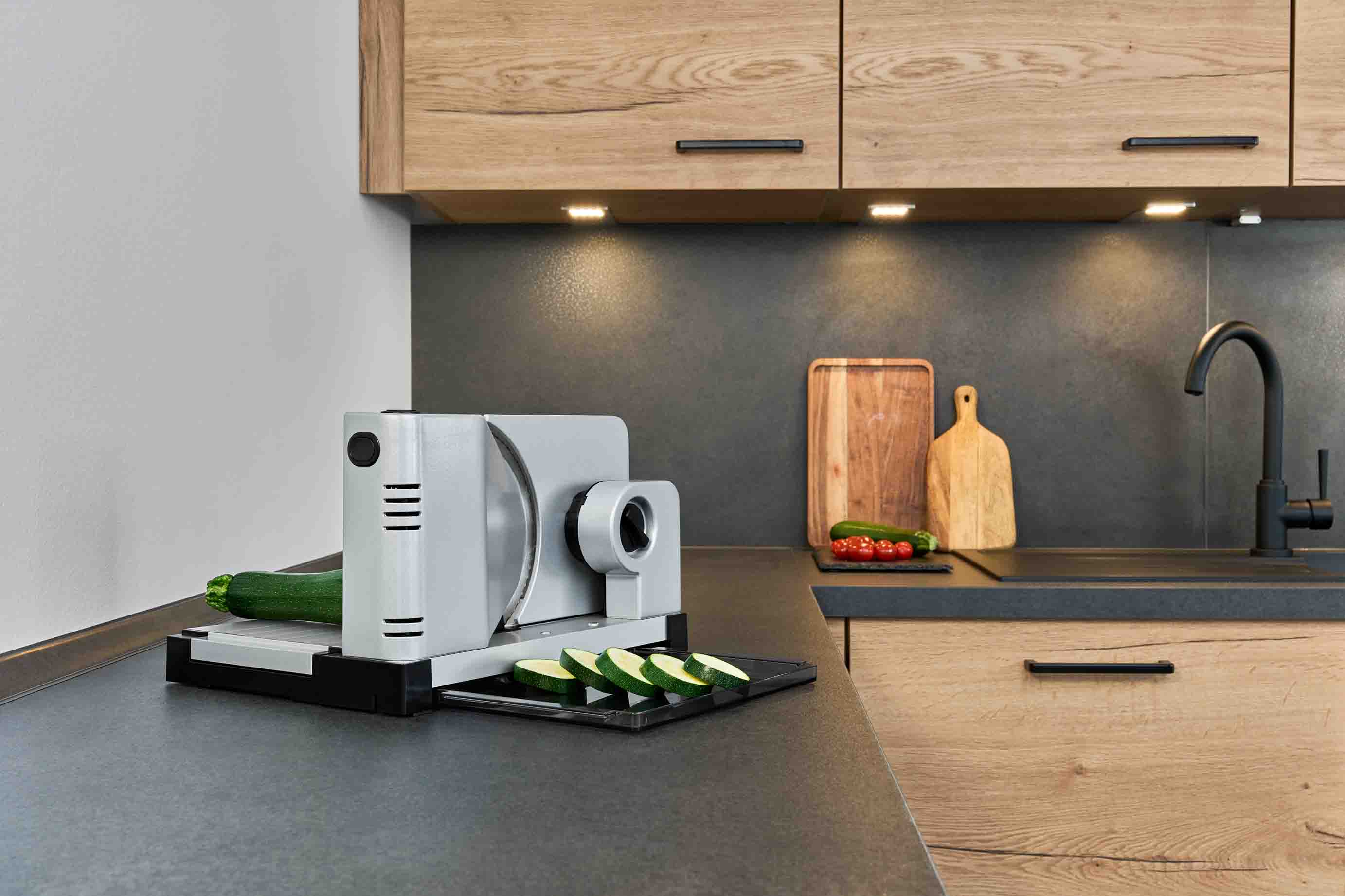 Elektrischer Allesschneider mit geschnittenen Zucchini, in moderner Küche