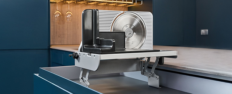 Ein Bild von einem Einbau-Allesschneider der aus einer Küchenschublade hervorkommt.