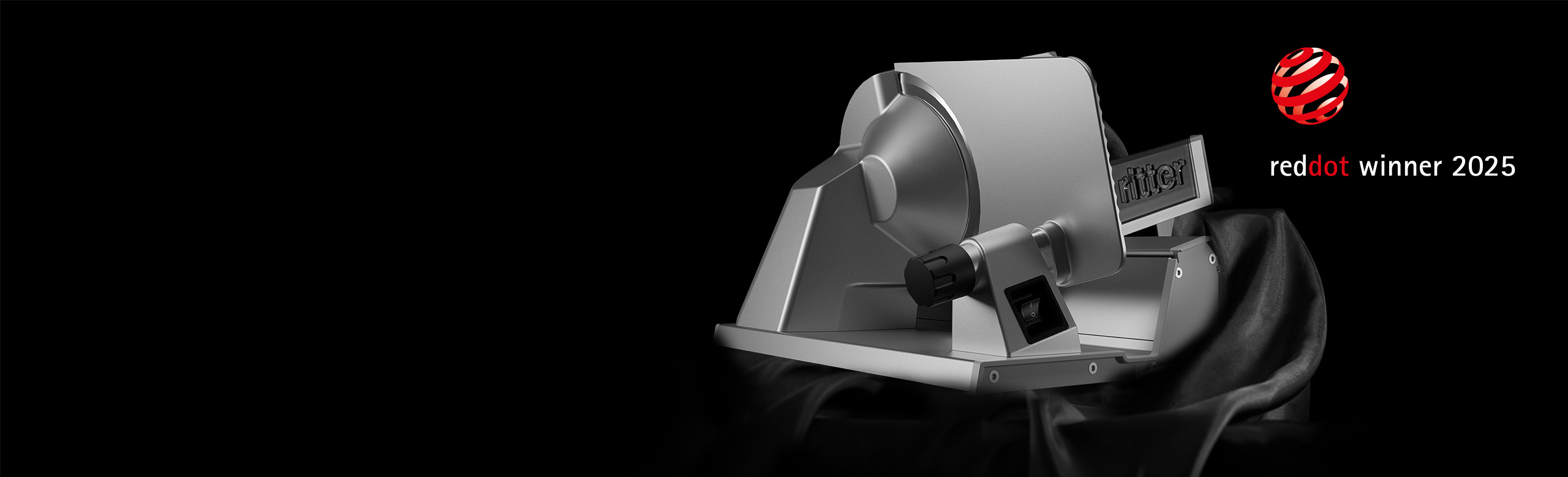 Ein Bild von einem Feinschneider, der aus einem schwarzen Tuch hervorkommt, und einer reddot winner 2025 Auszeichnung.